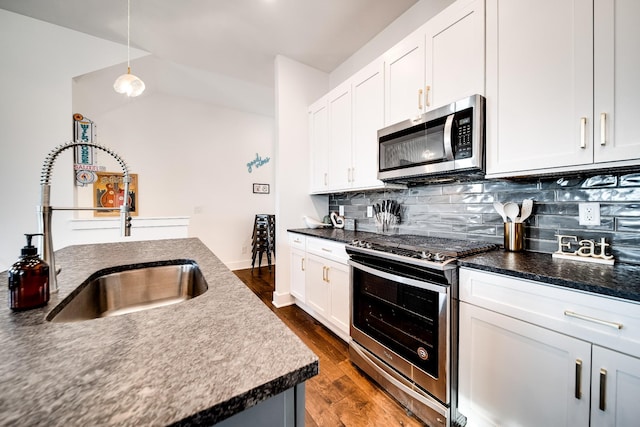 kitchen with dark countertops, appliances with stainless steel finishes, a sink, and tasteful backsplash