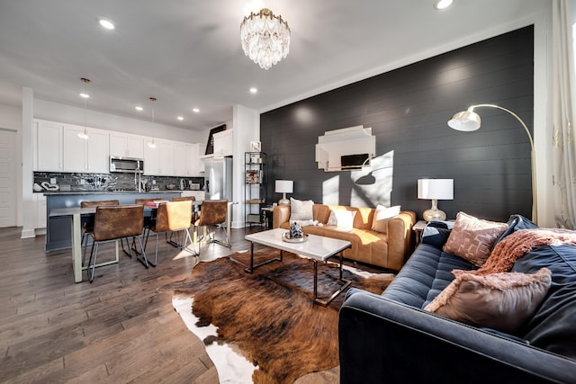 living room featuring dark wood-type flooring, recessed lighting, a chandelier, and wood walls