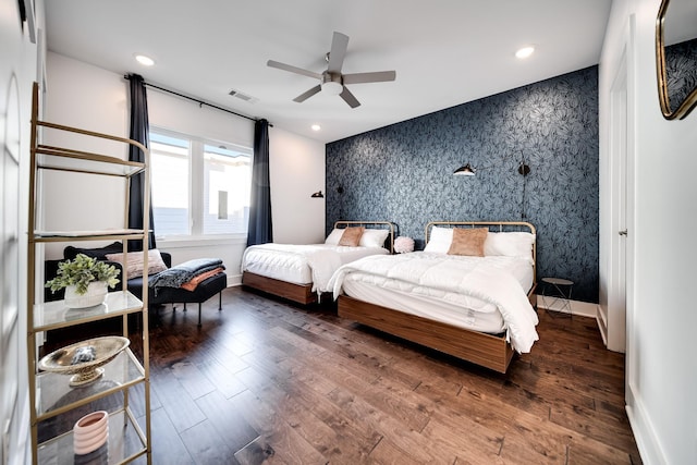 bedroom with wallpapered walls, visible vents, baseboards, and wood finished floors