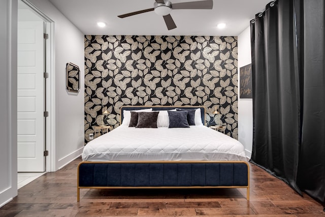 bedroom with recessed lighting, baseboards, wood finished floors, and an accent wall