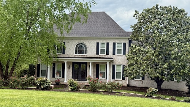 view of front facade featuring a porch, brick siding, and a front yard