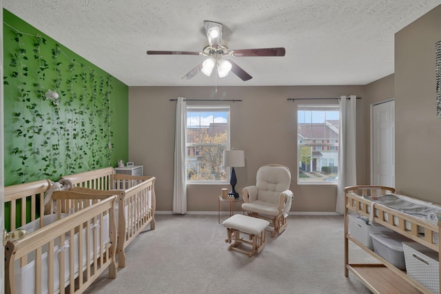 bedroom featuring a crib, multiple windows, baseboards, and a textured ceiling