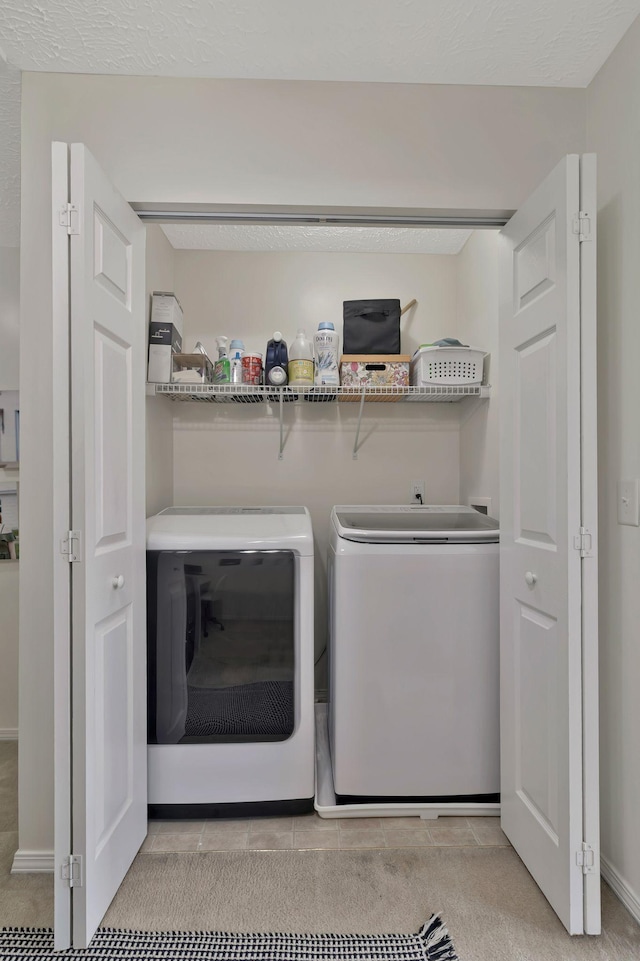 washroom featuring independent washer and dryer, light tile patterned flooring, laundry area, and baseboards