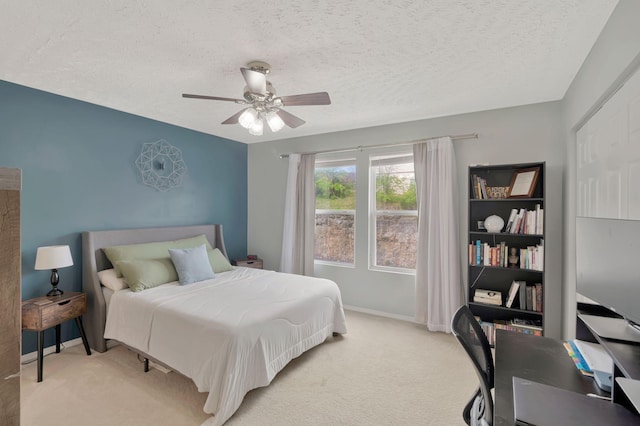 bedroom featuring baseboards, a ceiling fan, a textured ceiling, and light colored carpet
