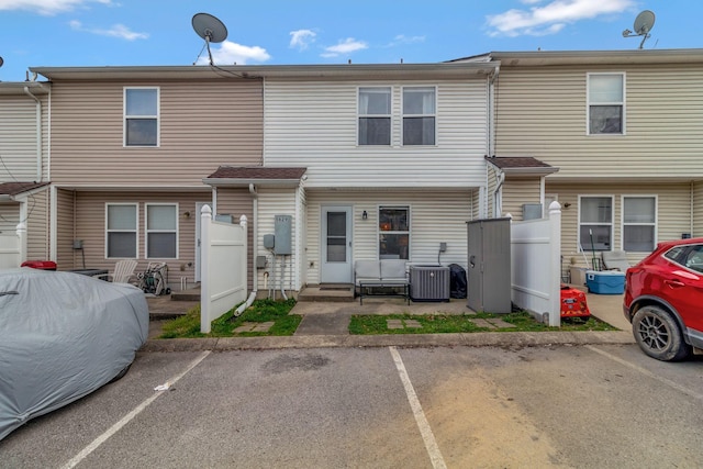 back of house featuring central AC and uncovered parking