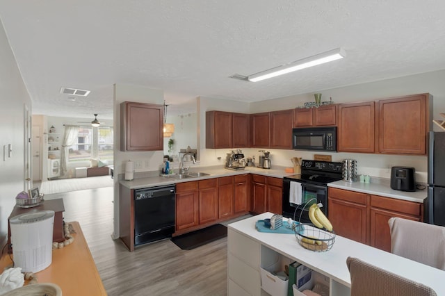 kitchen featuring visible vents, a sink, black appliances, and light countertops