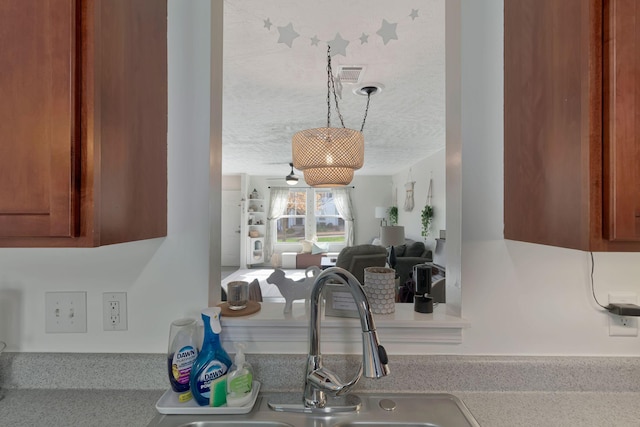 room details featuring a sink, light countertops, brown cabinetry, and visible vents