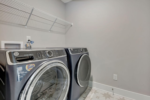 washroom featuring separate washer and dryer, laundry area, and baseboards