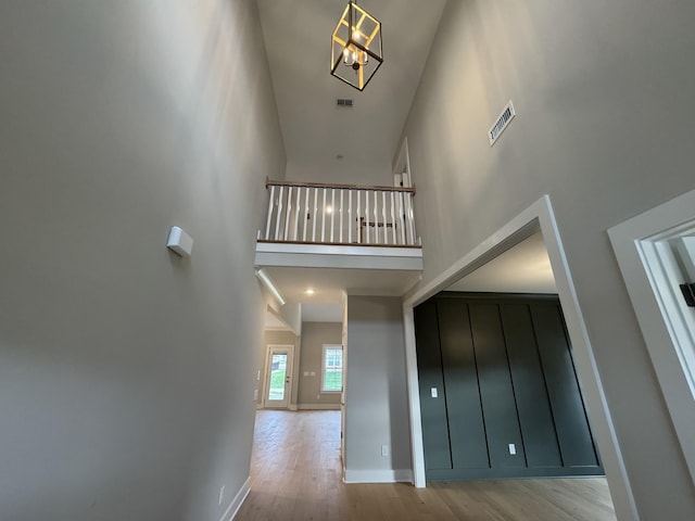 interior space featuring visible vents, baseboards, a towering ceiling, and wood finished floors