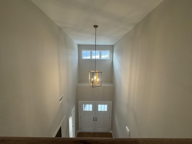 foyer entrance featuring a towering ceiling, visible vents, and a chandelier