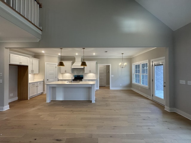 kitchen with crown molding, high vaulted ceiling, a chandelier, and custom exhaust hood