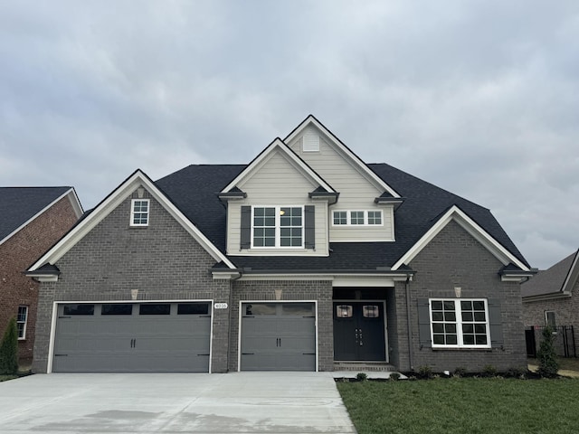 craftsman-style home with brick siding, driveway, a front yard, and roof with shingles