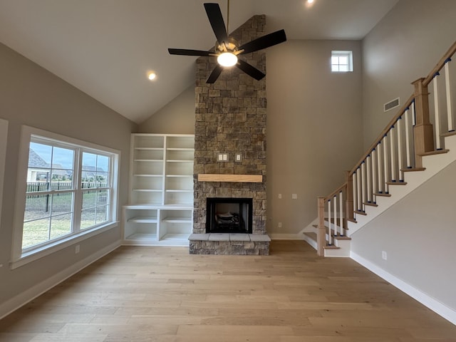 unfurnished living room with stairway, high vaulted ceiling, light wood finished floors, and visible vents
