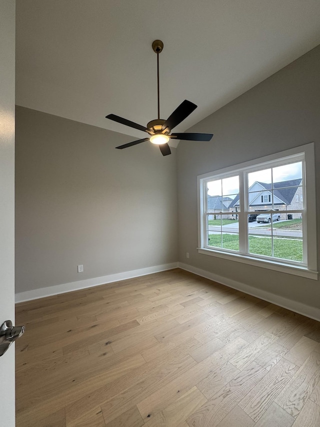 empty room featuring light wood-style floors, baseboards, a ceiling fan, and lofted ceiling