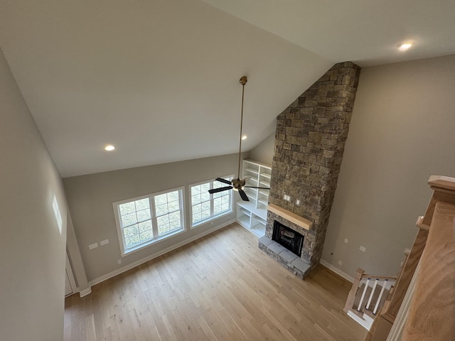 unfurnished living room with a ceiling fan, a stone fireplace, vaulted ceiling, wood finished floors, and recessed lighting