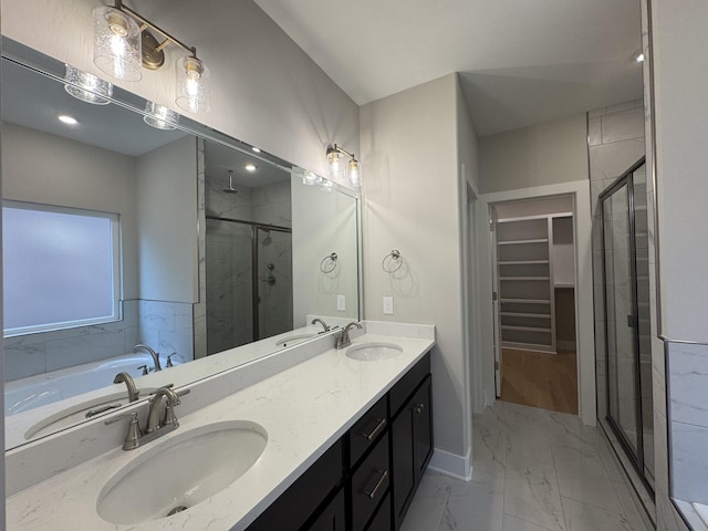 bathroom featuring a sink, a spacious closet, a shower stall, and marble finish floor