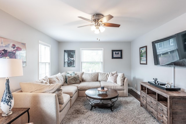 living room with a ceiling fan, baseboards, and wood finished floors
