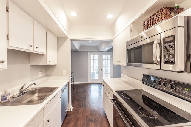 kitchen with dark wood-type flooring, a raised ceiling, white cabinets, a sink, and stainless steel appliances