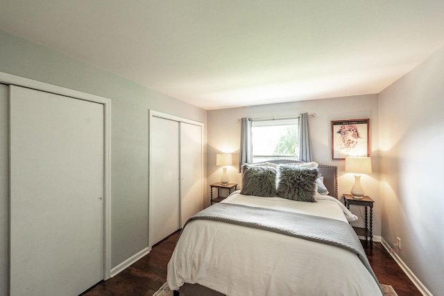bedroom with baseboards, multiple closets, and dark wood-type flooring