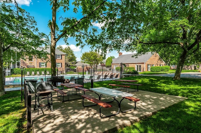 view of home's community with a lawn, a swimming pool, and fence