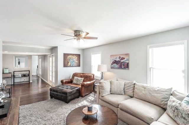 living area featuring baseboards, a ceiling fan, and dark wood-style flooring