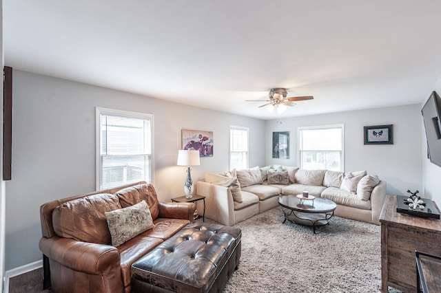 living area with baseboards and a ceiling fan