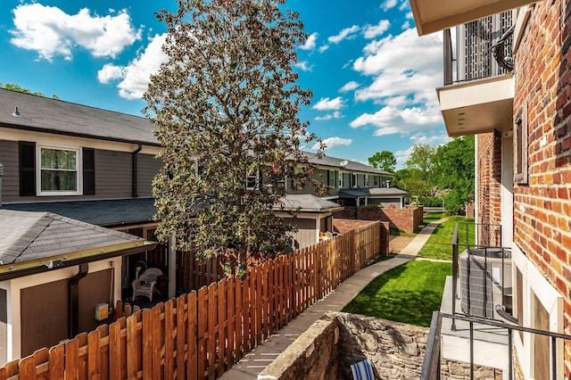view of side of property with brick siding, fence, and a balcony