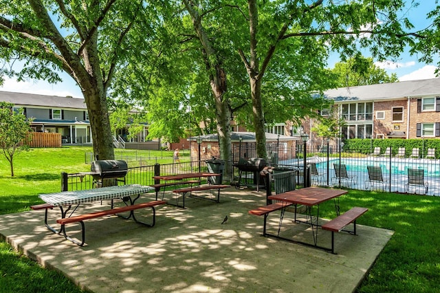 view of community featuring a yard, fence, a patio area, and a pool