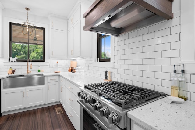 kitchen with decorative backsplash, gas range, light stone countertops, a sink, and custom exhaust hood