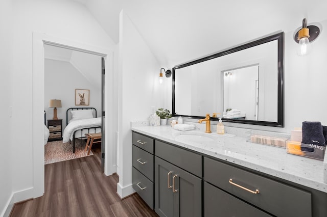 bathroom with vanity, vaulted ceiling, wood finished floors, and connected bathroom