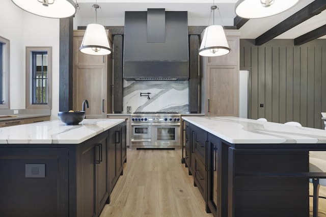 kitchen featuring a center island, light wood finished floors, range hood, and range with two ovens