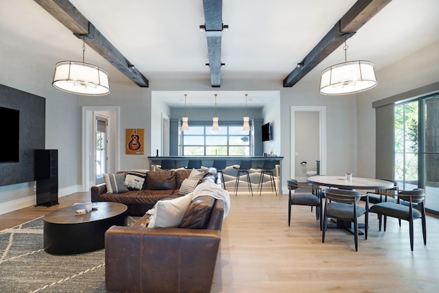 living area with baseboards, beam ceiling, and light wood-type flooring