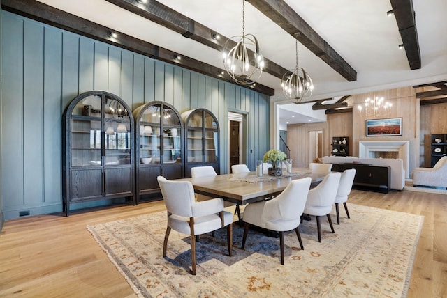 dining room with wood finished floors, beam ceiling, and a chandelier