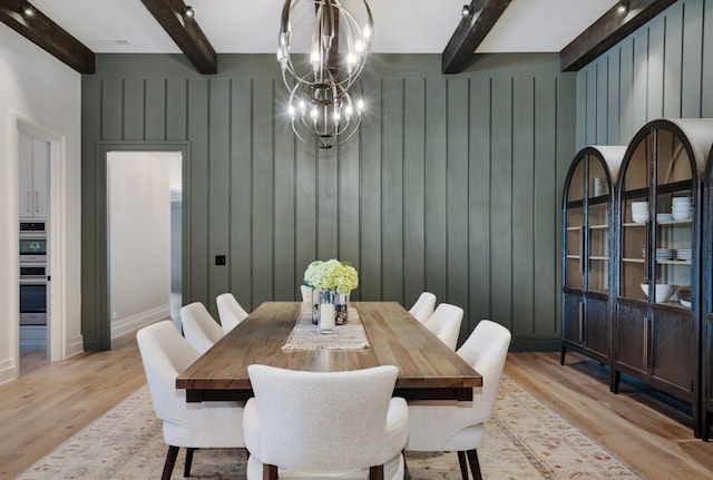 dining room with baseboards, light wood-style flooring, a notable chandelier, and beamed ceiling