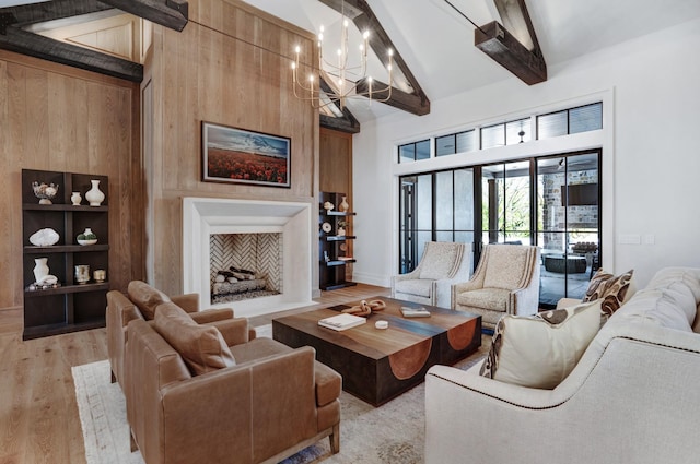 living area with beamed ceiling, baseboards, high vaulted ceiling, a chandelier, and light wood finished floors
