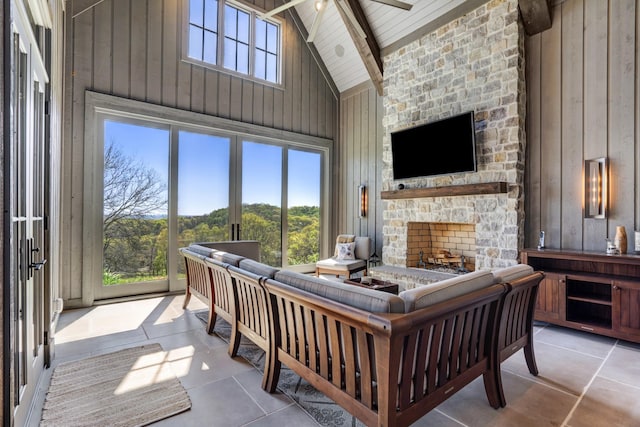 tiled living room featuring wooden walls, high vaulted ceiling, beamed ceiling, and a stone fireplace