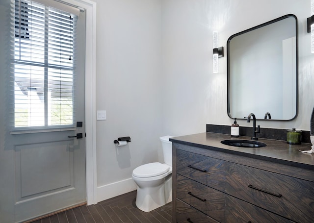 bathroom with toilet, baseboards, wood finished floors, and vanity