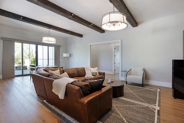 living area featuring baseboards, beam ceiling, and wood finished floors