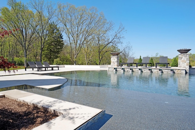 view of swimming pool with an infinity pool and a patio