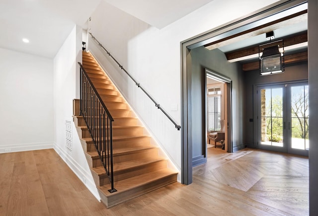 stairs featuring baseboards, french doors, beam ceiling, and wood finished floors