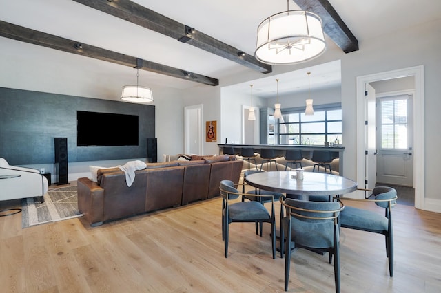 dining room with baseboards, light wood-style flooring, and beam ceiling