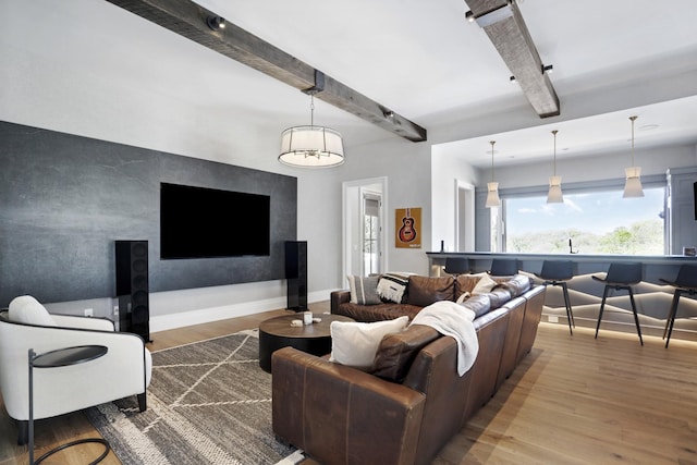 living area featuring baseboards, beamed ceiling, and wood finished floors