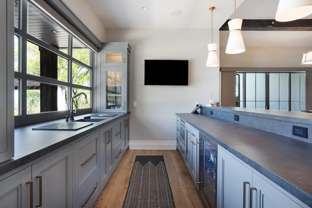 bar featuring built in microwave, baseboards, light wood-type flooring, wine cooler, and pendant lighting