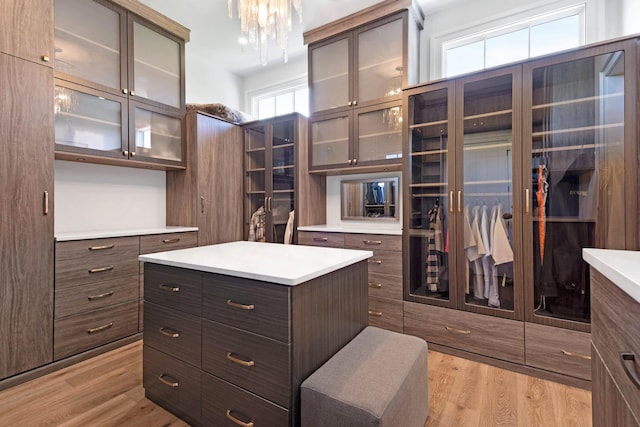 walk in closet with light wood-style flooring and a notable chandelier