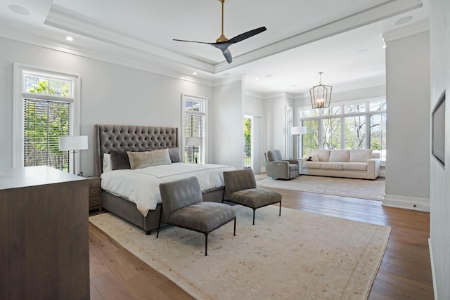 bedroom with crown molding, a chandelier, wood finished floors, and a raised ceiling