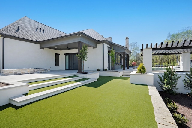 back of house with a pergola, stucco siding, a chimney, a ceiling fan, and a patio area