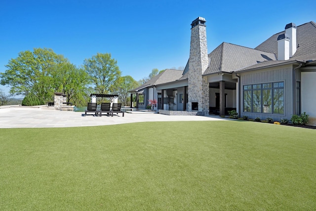 back of house with a patio, a chimney, a yard, and a fireplace