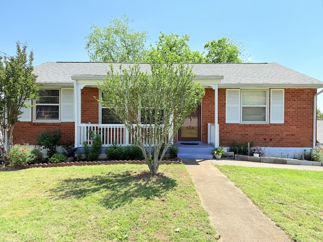 view of front facade with a shingled roof, a porch, a front lawn, and brick siding