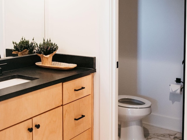 bathroom featuring toilet, marble finish floor, and vanity