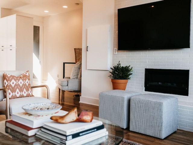 living area featuring a brick fireplace, recessed lighting, and wood finished floors